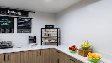 Eine Theke in einer Bäckerei mit Speisekarte, einer Auswahl an Backwaren und Schalen mit frischem Obst.