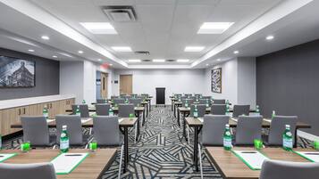 A conference room with multiple tables, chairs, and water bottles.