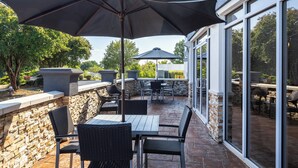Un espace patio agrémenté de murs en pierre, de mobilier d’extérieur et de grandes fenêtres.
