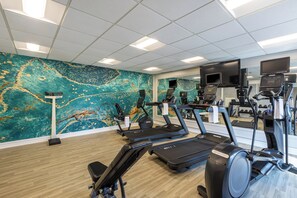 A gym with treadmills, stationary bikes, and a mirrored wall.
