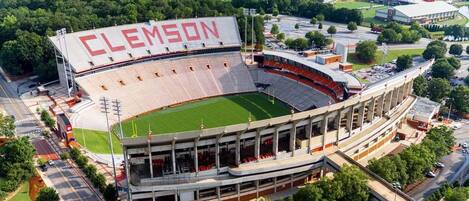 A stadium with 'CLEMSON' written on the upper deck, surrounded by greenery and a body of water.