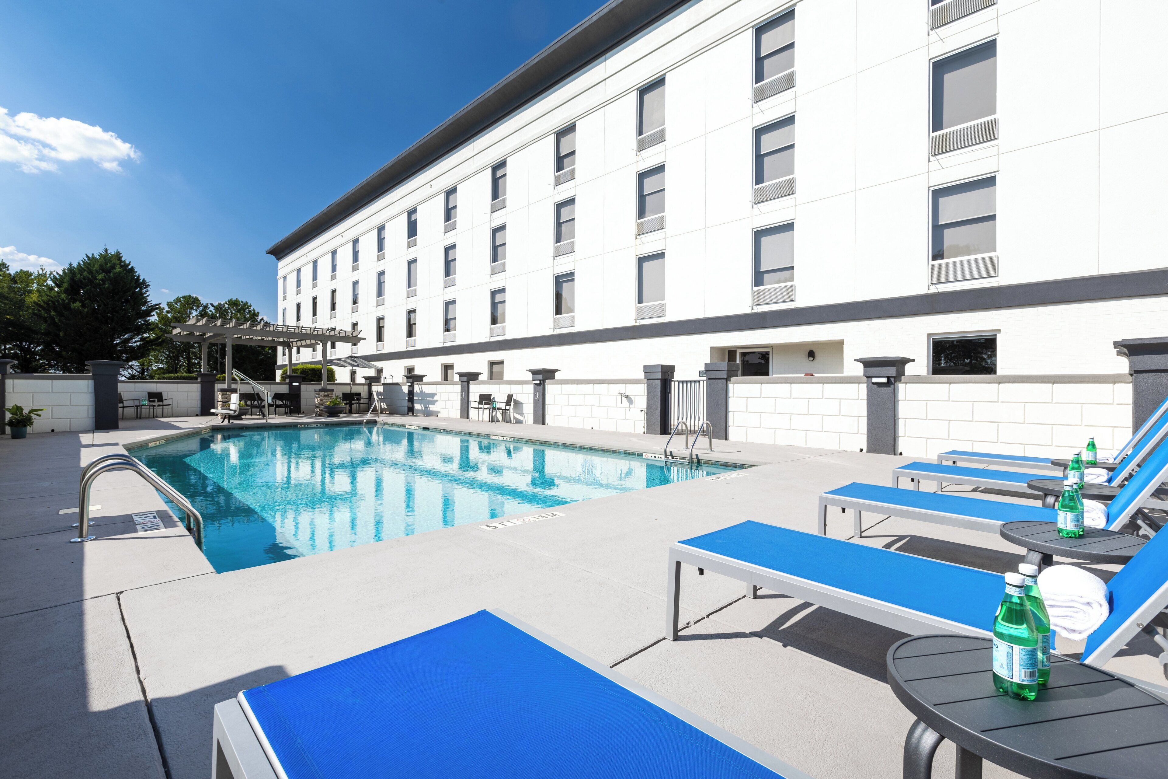 A pool area with lounge chairs and a building in the background.