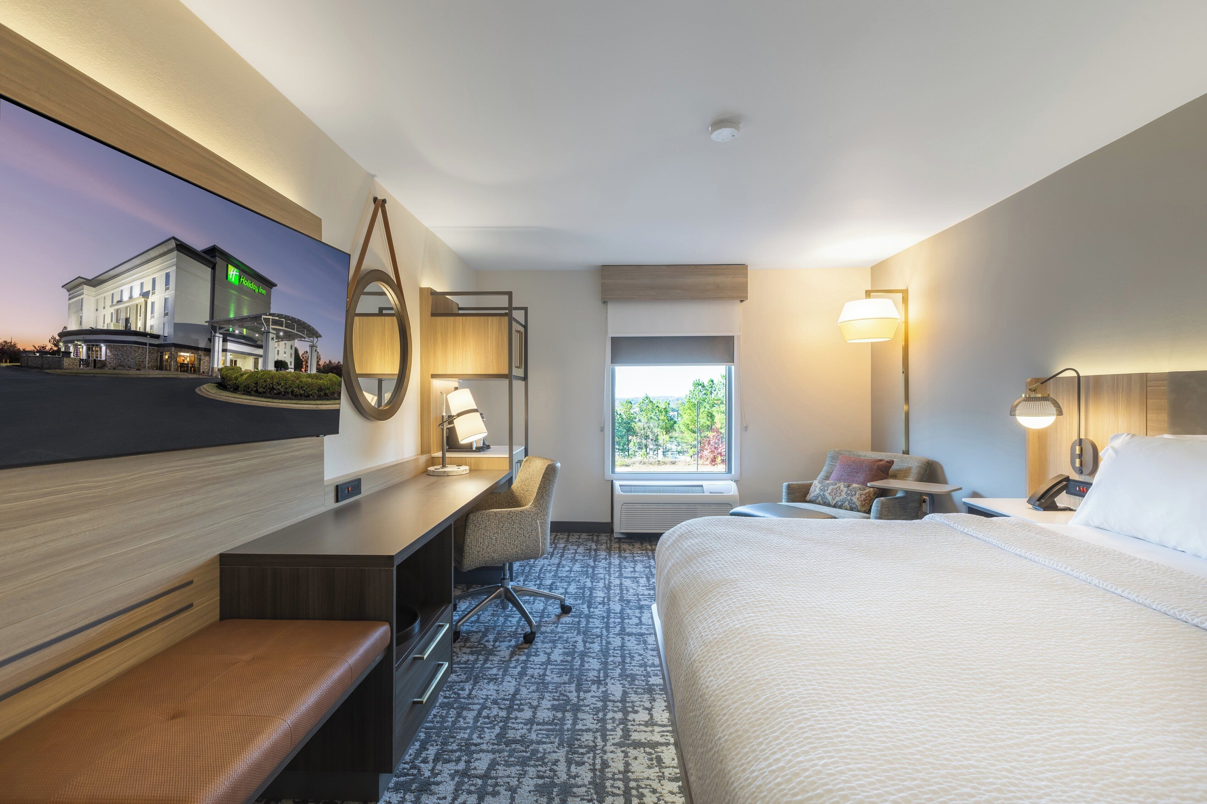 Ein Hotelzimmer mit Bett, Schreibtisch, Stuhl und einem großen Fenster.