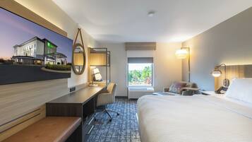 Ein Hotelzimmer mit Bett, Schreibtisch, Stuhl und einem großen Fenster.
