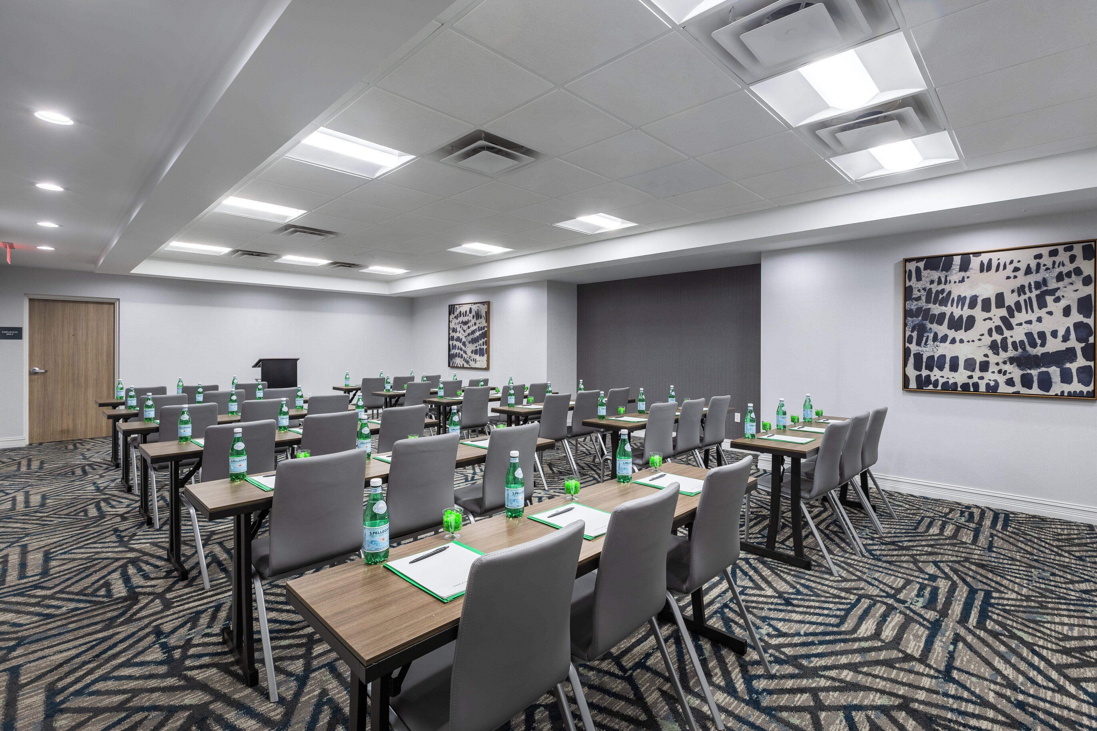 A conference room with multiple tables, chairs, and water bottles.