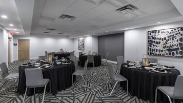 A conference room with round tables, chairs, and a patterned carpet.
