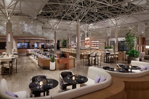 A spacious hotel lobby with multiple seating areas, a bar, and a restaurant.