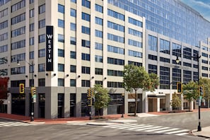 A modern Westin hotel with a glass facade, multiple floors, and a prominent entrance with a red awning.