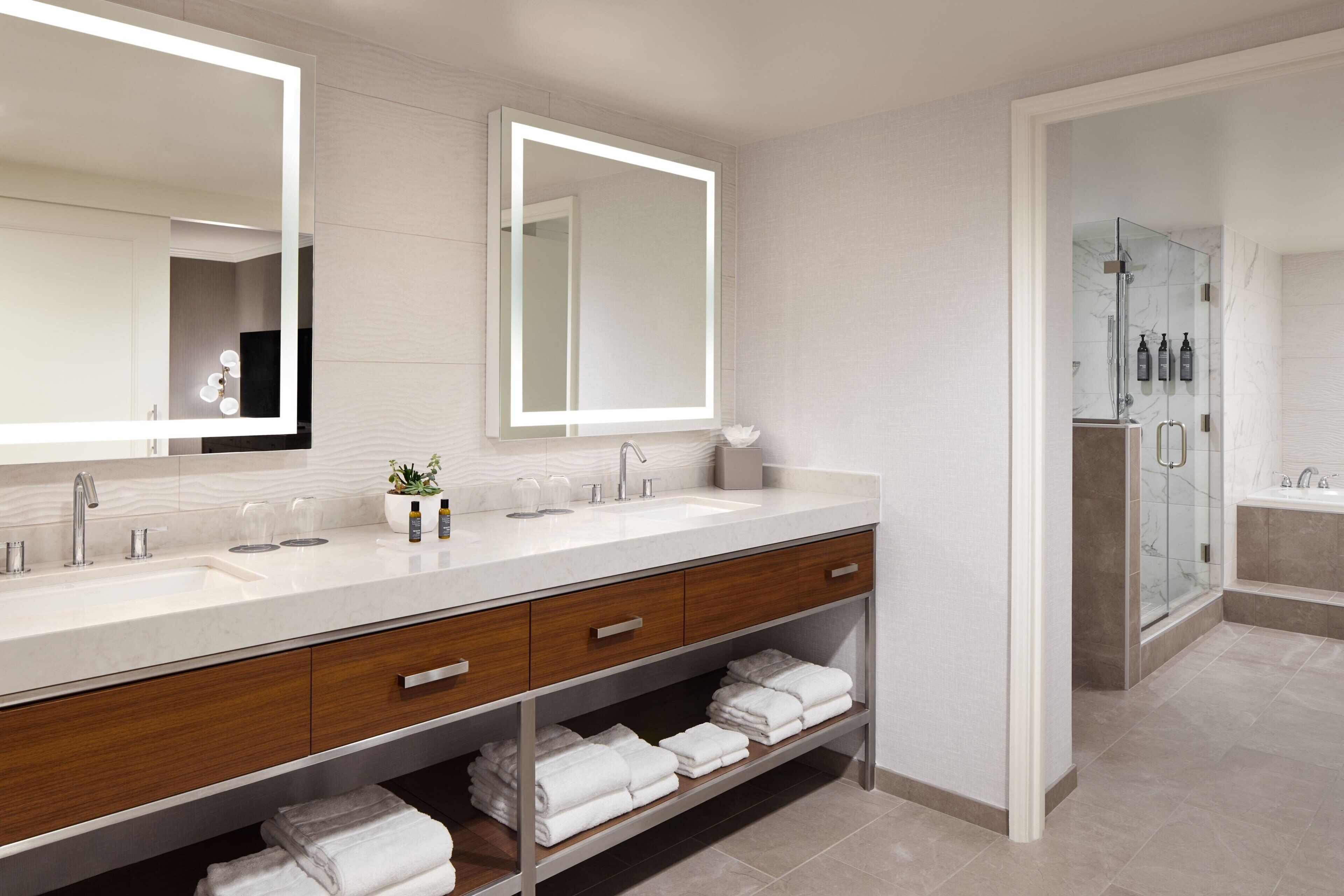 Un bagno moderno con un doppio lavabo, uno specchio grande e una cabina doccia in vetro.