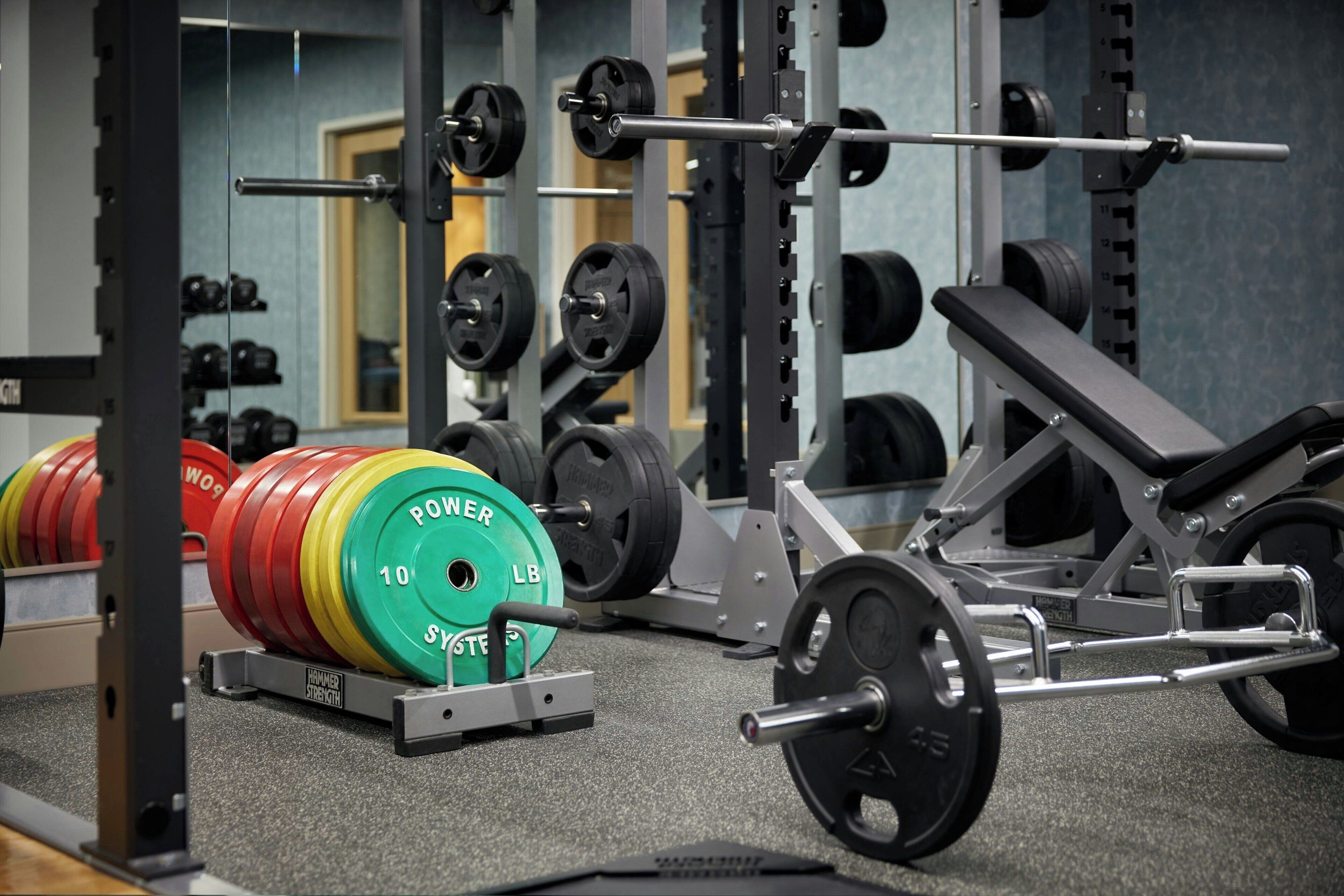 Un gimnasio con equipo de levantamiento de pesas, incluyendo barras y discos.