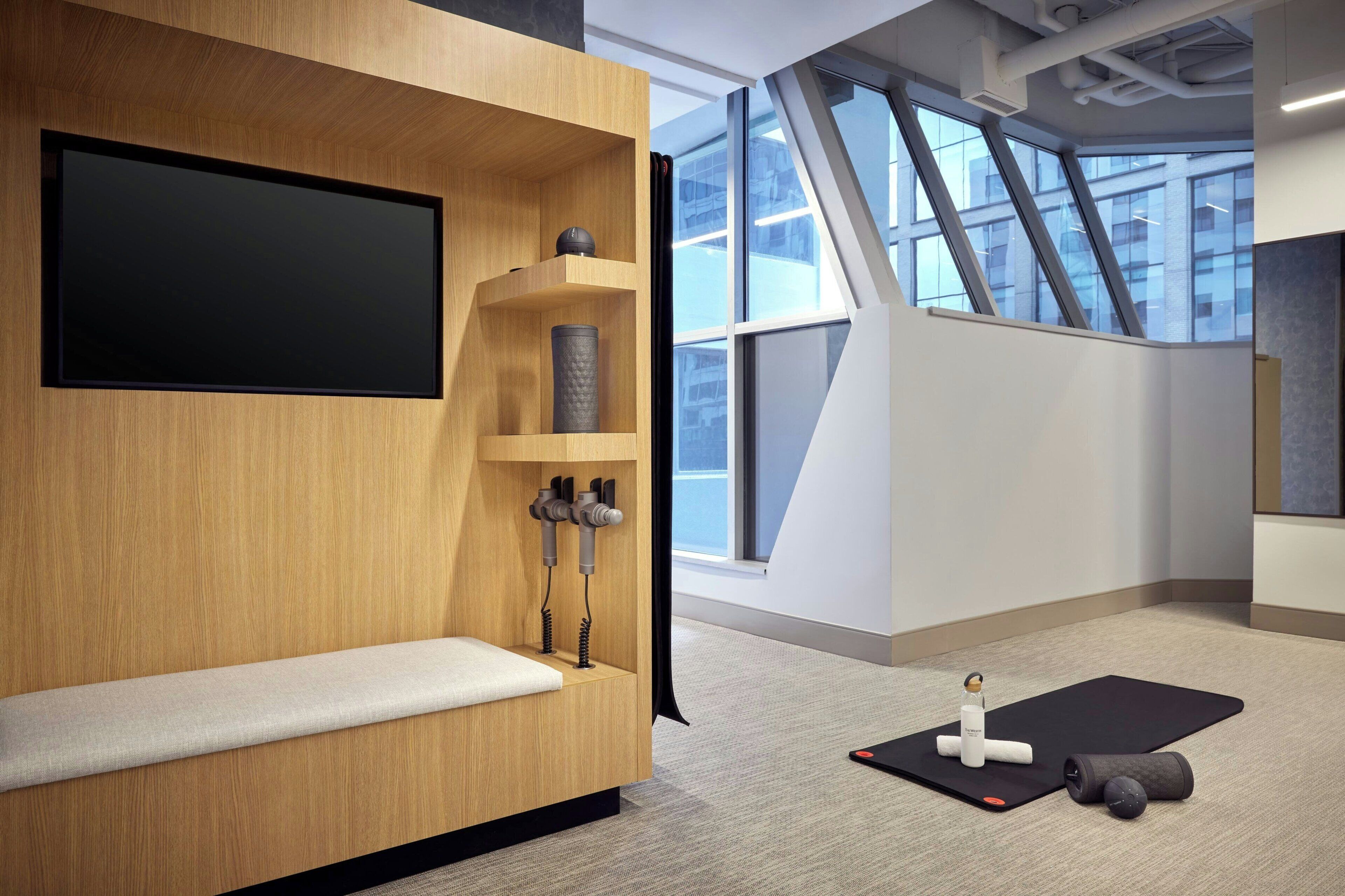 Une pièce moderne avec un mur en bois, un tapis noir et du matériel d’exercice.