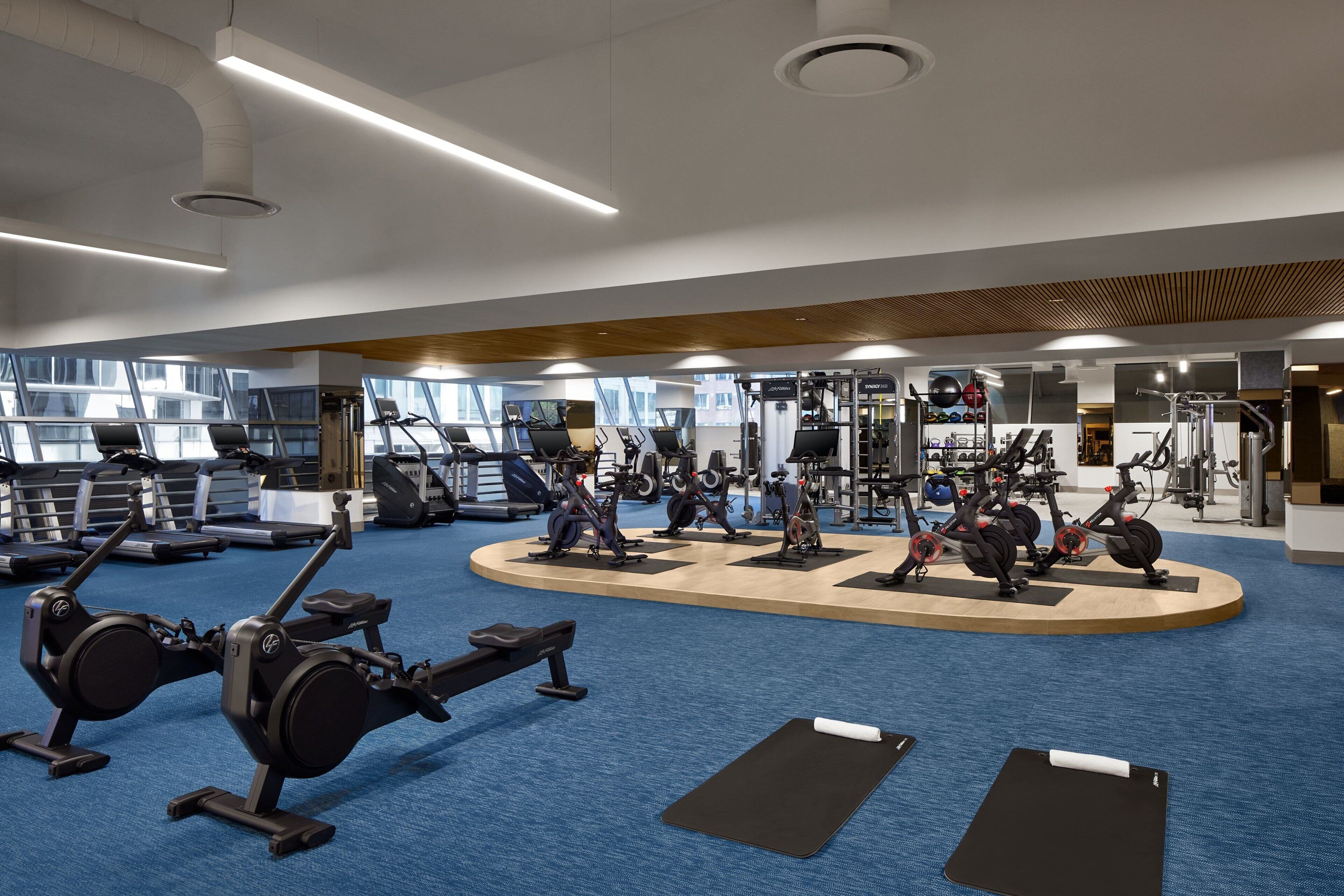 Un gimnasio moderno con diverso equipo de ejercicio, incluyendo cintas de correr, bicicletas estáticas y máquinas de pesas.