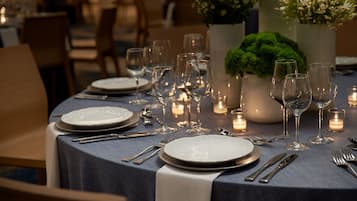 A dining table set with plates, cutlery, and wine glasses, surrounded by candles and floral arrangements.