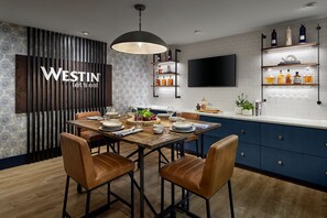 A modern kitchen with a wooden dining table, brown leather chairs, and a large pendant light.