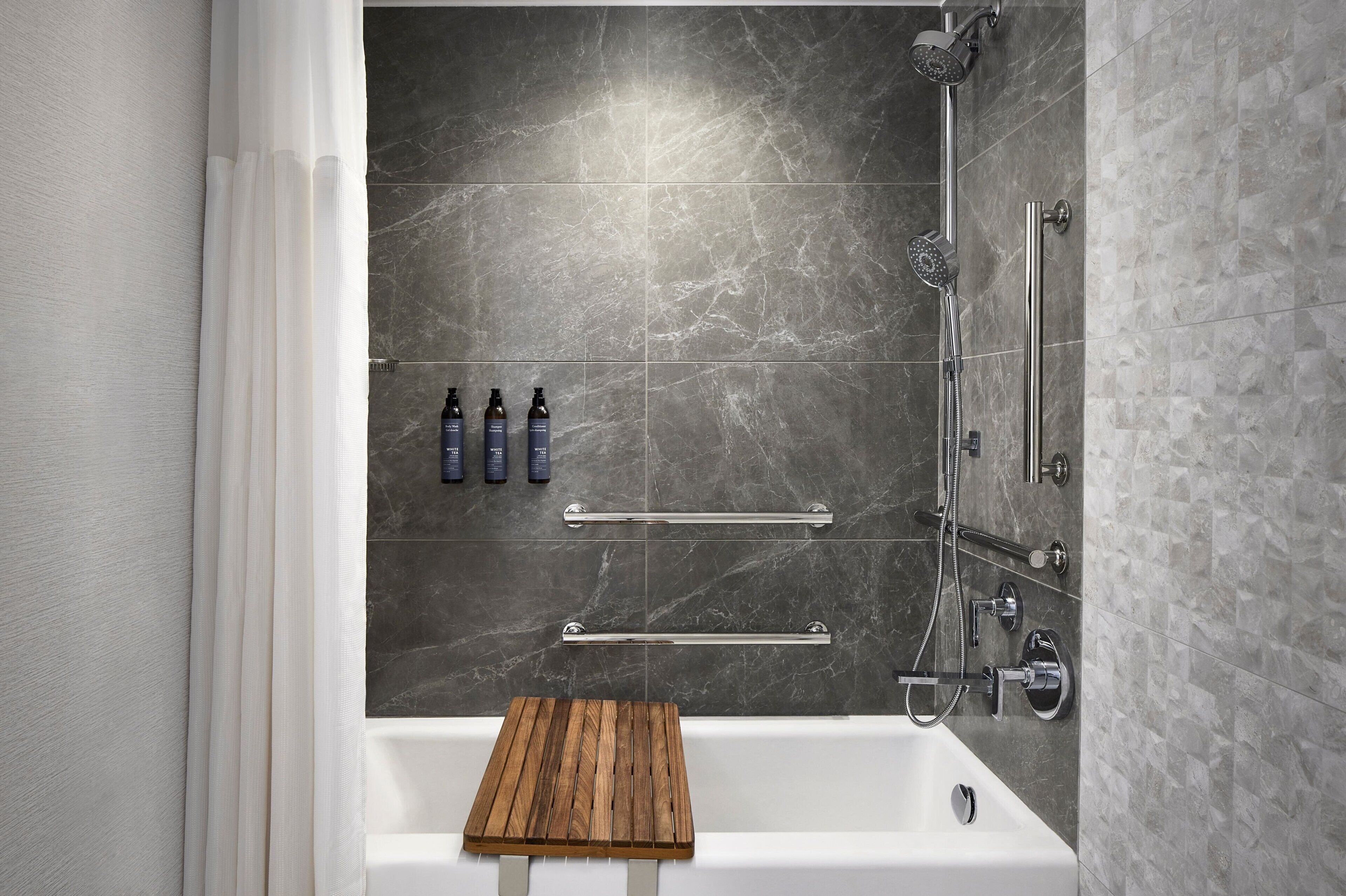 A modern bathroom with a bathtub, shower, and a wooden tray.