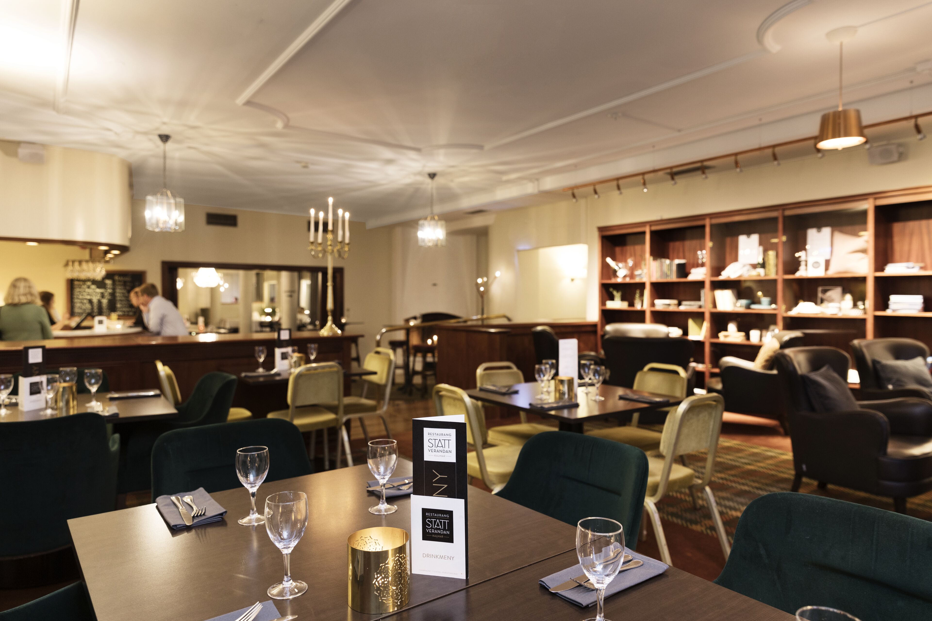 A restaurant with tables set for dining, a bar area, and a seating area with chairs and a sofa.