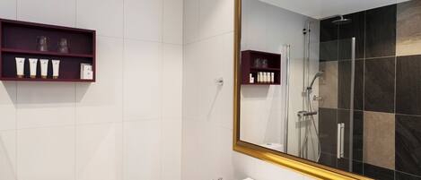 A modern bathroom with a large mirror, a shower, and a toilet.