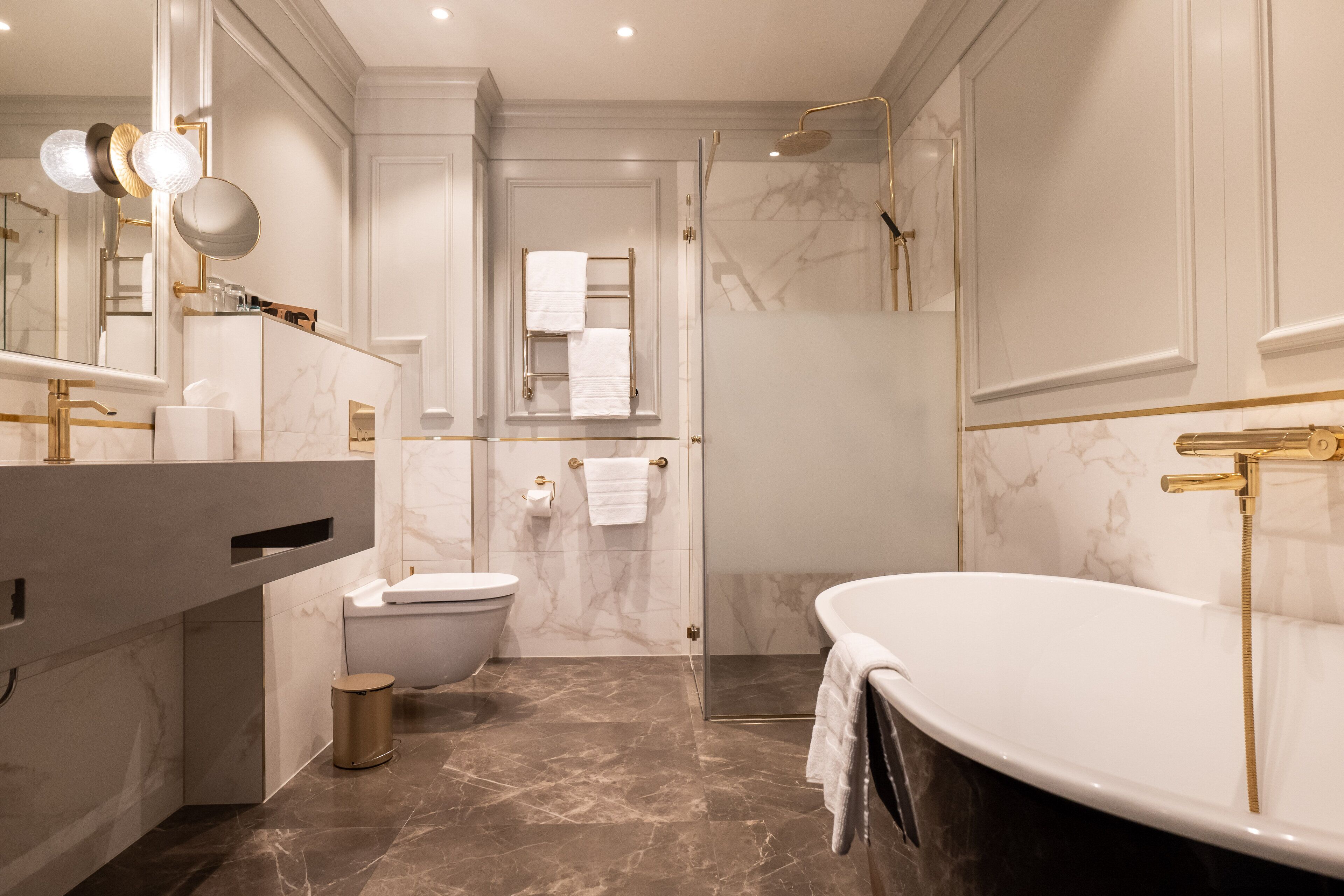 Un baño moderno con una bañera independiente, inodoro y ducha con mampara de vidrio.