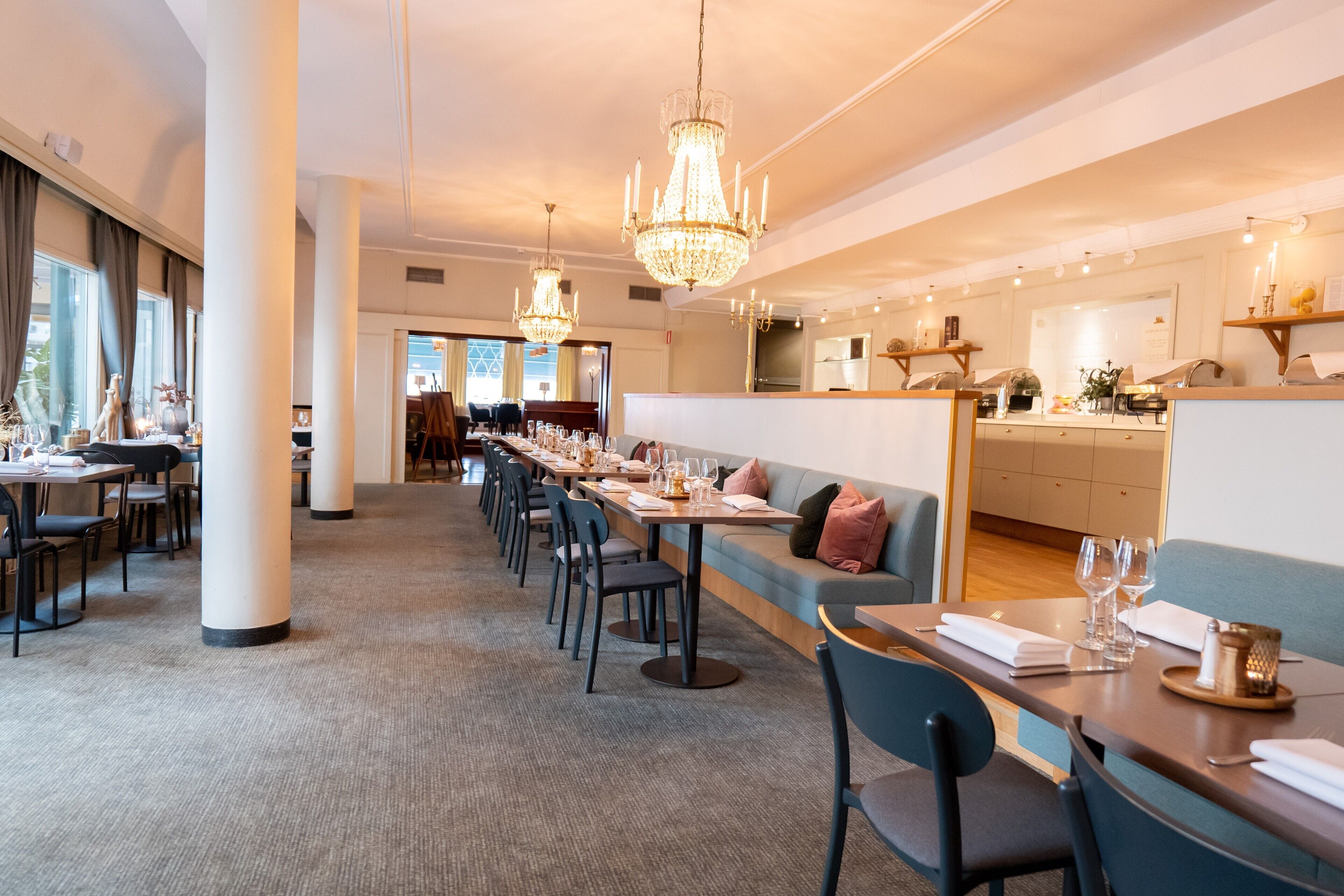 A hotel dining area with long tables, chairs, and a bar counter.