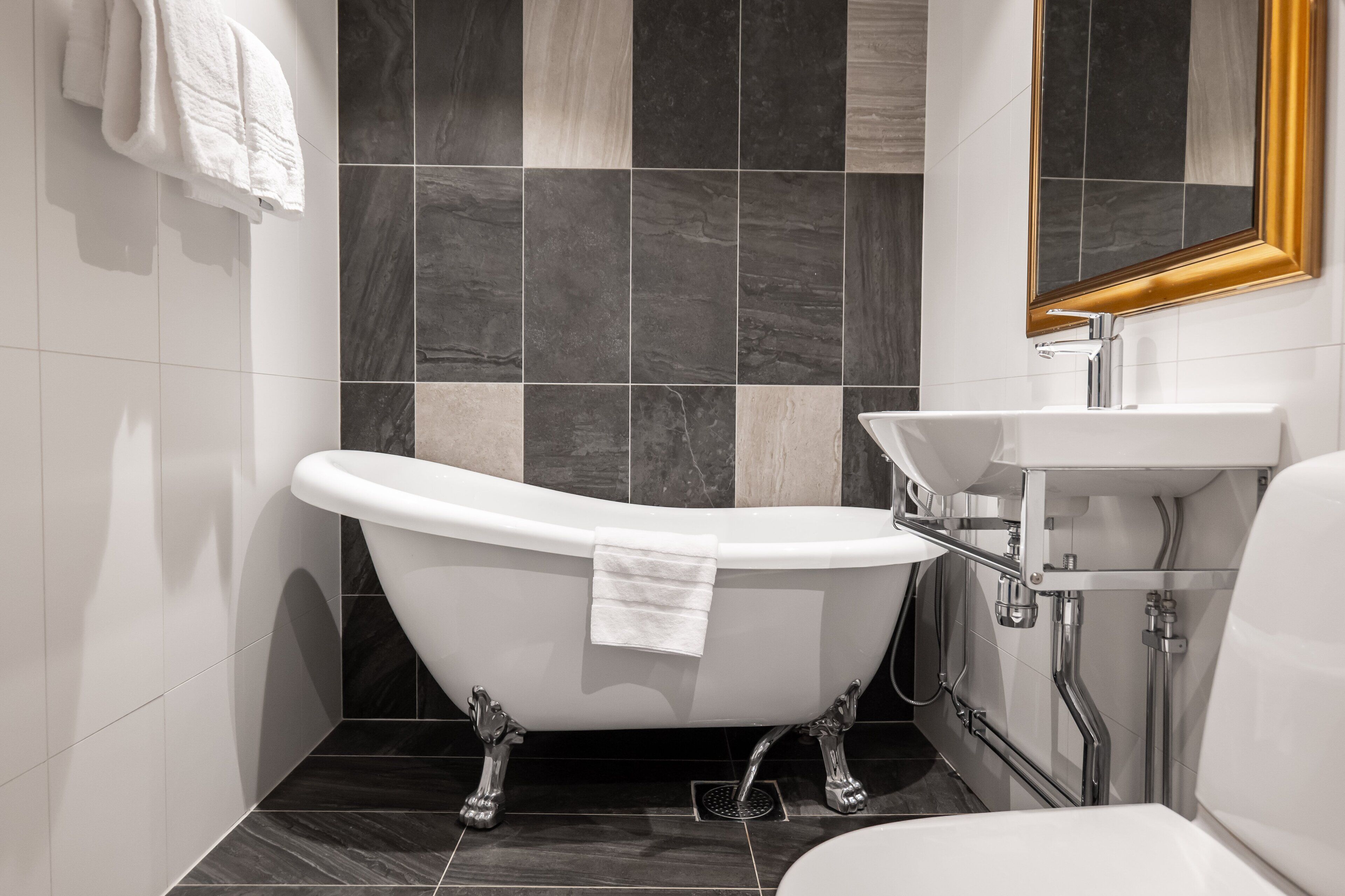 Un baño con una bañera independiente, un lavabo y un espejo.