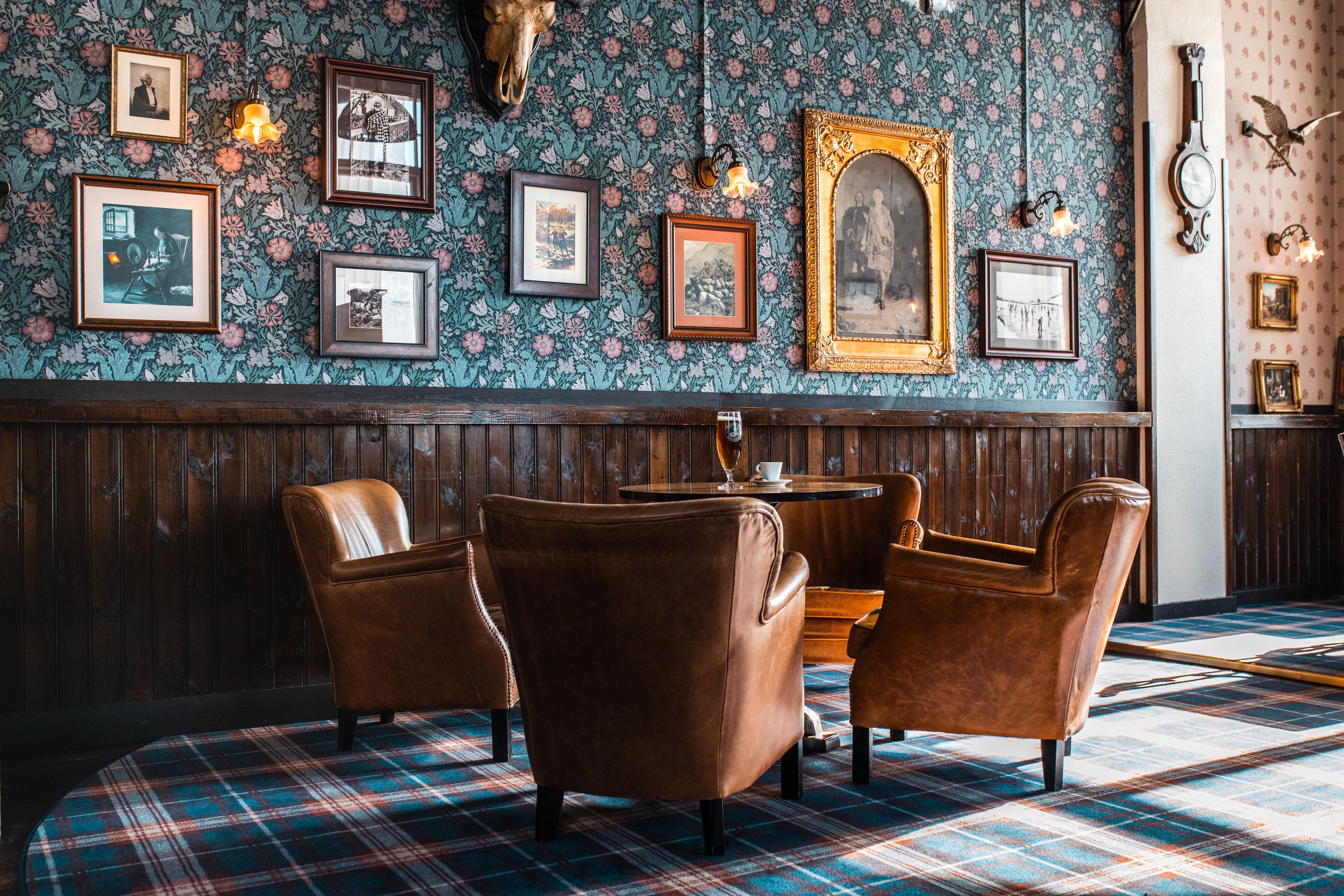 A room with a plaid carpet, wooden paneling, and a wall adorned with framed pictures and a skull.