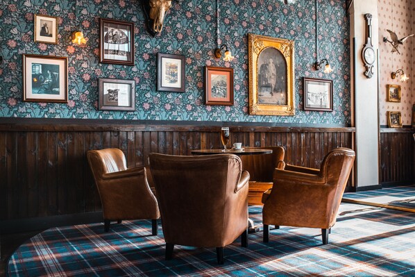 A room with a plaid carpet, wooden paneling, and a wall adorned with framed pictures and a skull.