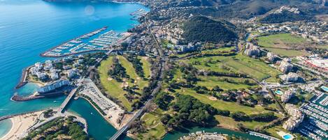 Vista aérea de un complejo turístico costero con puerto deportivo, campo de golf y zonas residenciales.