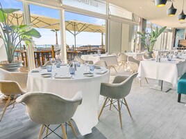 Un restaurante con mesas redondas, sillas y plantas en macetas.