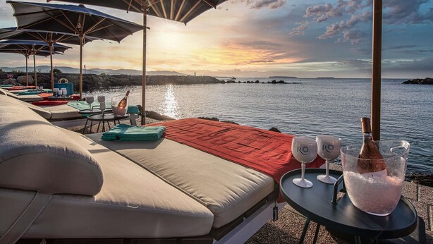 A seaside lounge with sun loungers, umbrellas, and a view of the sunset over the water. - Pullman Cannes Mandelieu (Mandelieu-La-Napoule)
