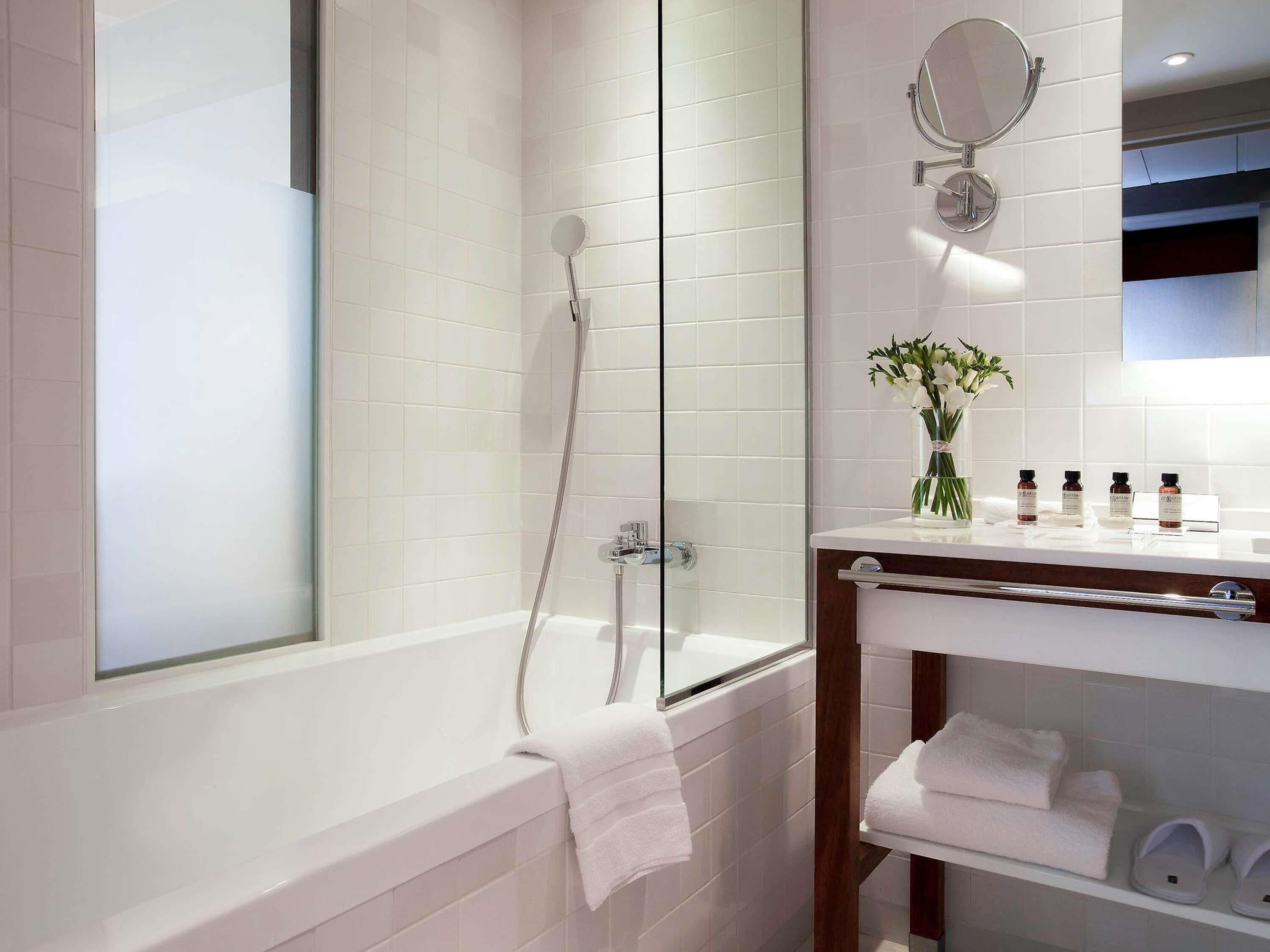 Une salle de bain moderne avec une douche à parois de verre, une baignoire blanche et un meuble-lavabo avec des articles de toilette.