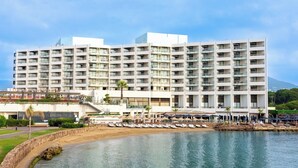 A large hotel with multiple floors, balconies, and a beach area with sun loungers. - Pullman Cannes Mandelieu (Mandelieu-La-Napoule)