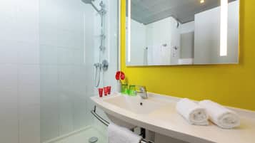 A modern bathroom with a white sink, a large mirror, and a glass shower enclosure.