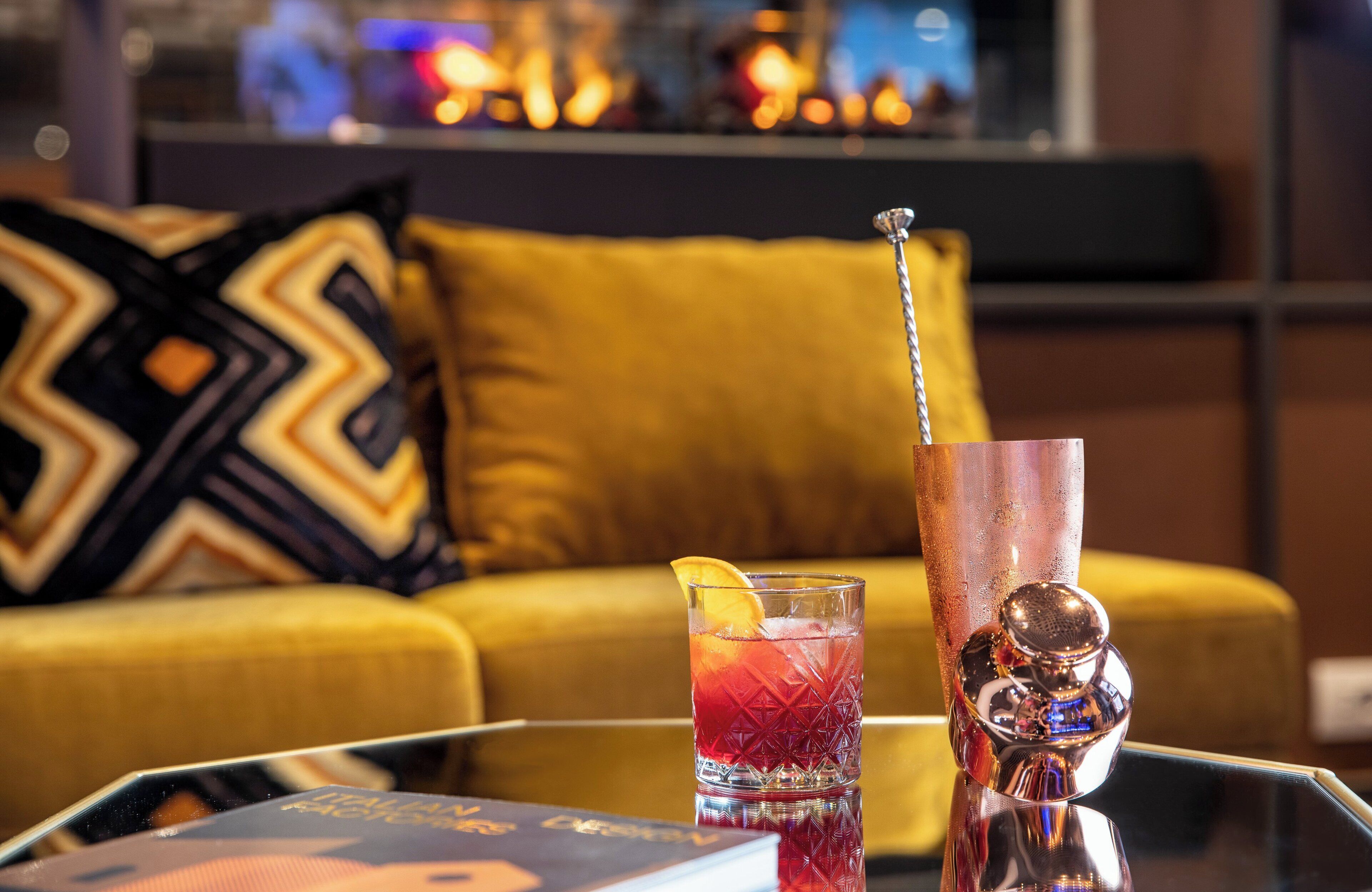 Een cocktailglas met een rietje en een citroenpartje op een glazen tafel.