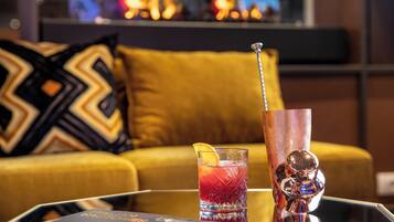A cocktail glass with a straw and a lemon wedge on a glass table.