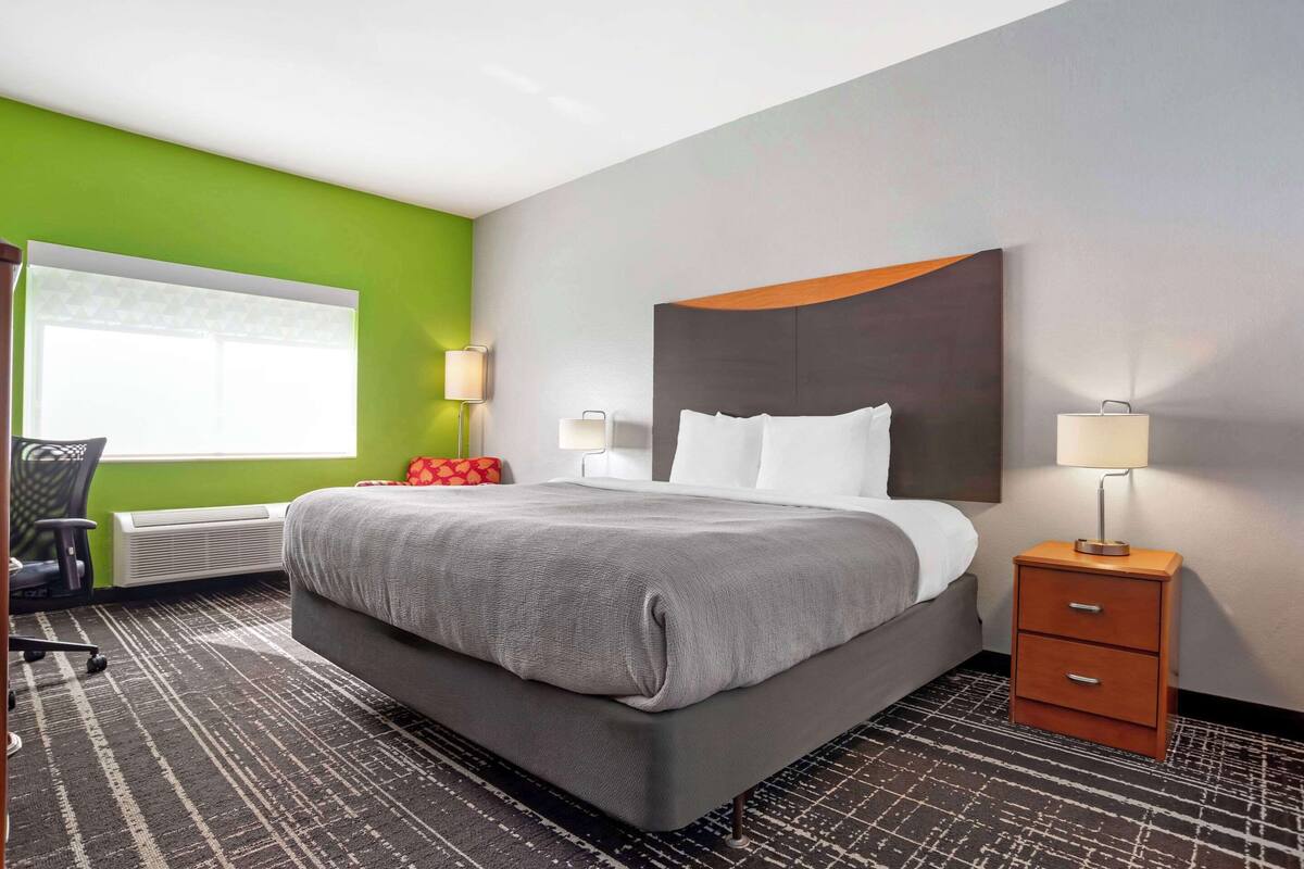 A modern hotel room with a large bed, a desk, and a chair.