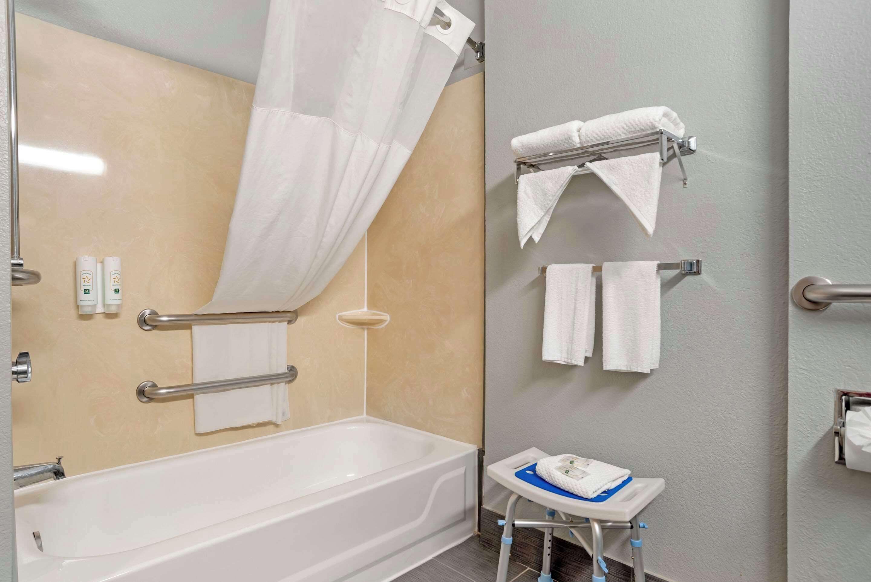 A modern bathroom with a bathtub, a shower with a glass door, and a small sink with a towel rack.