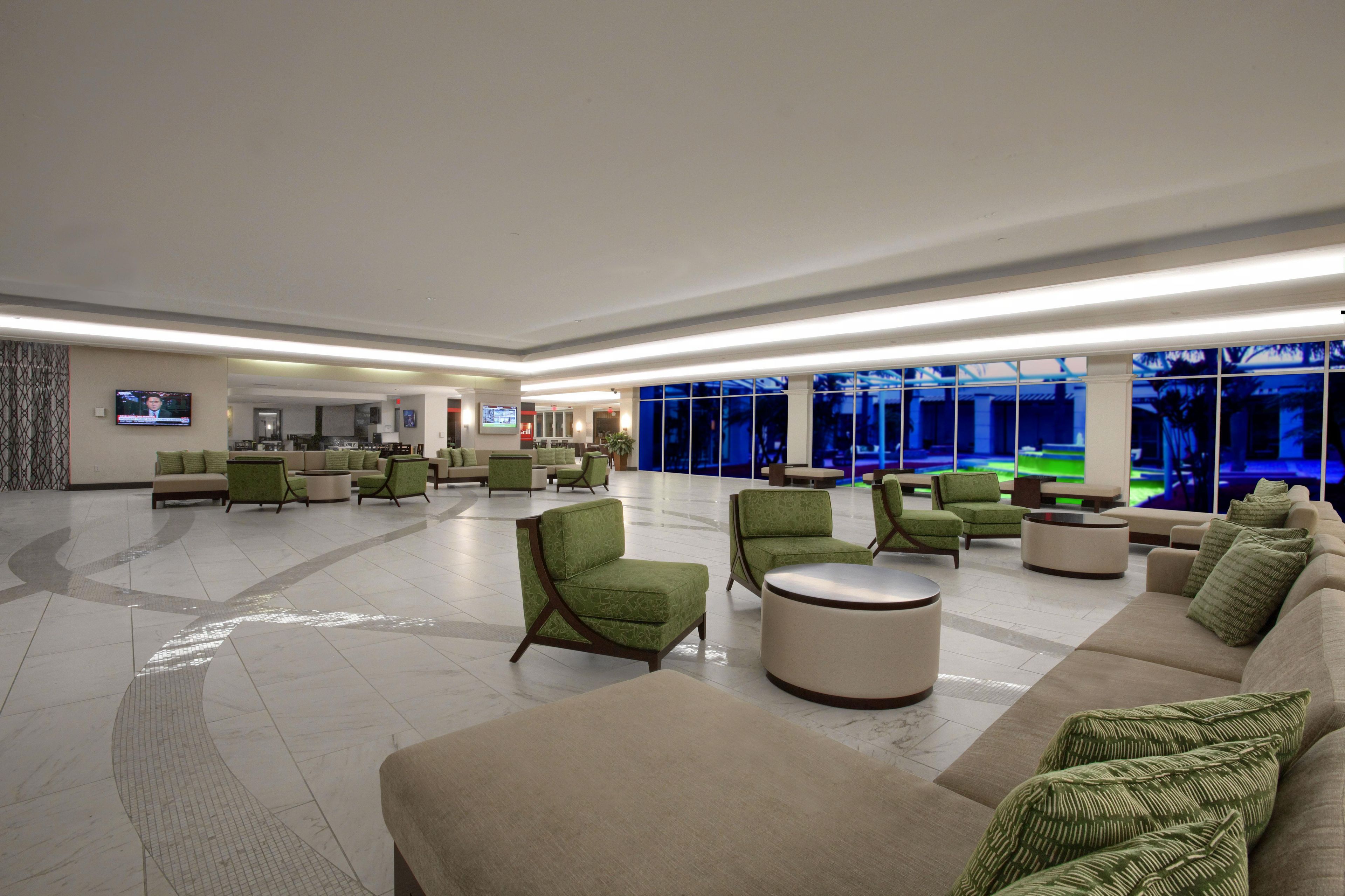 A spacious lobby with multiple seating areas, including sofas and armchairs, and a large television screen.