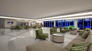 A spacious lobby with multiple seating areas, including sofas and armchairs, and a large television screen.