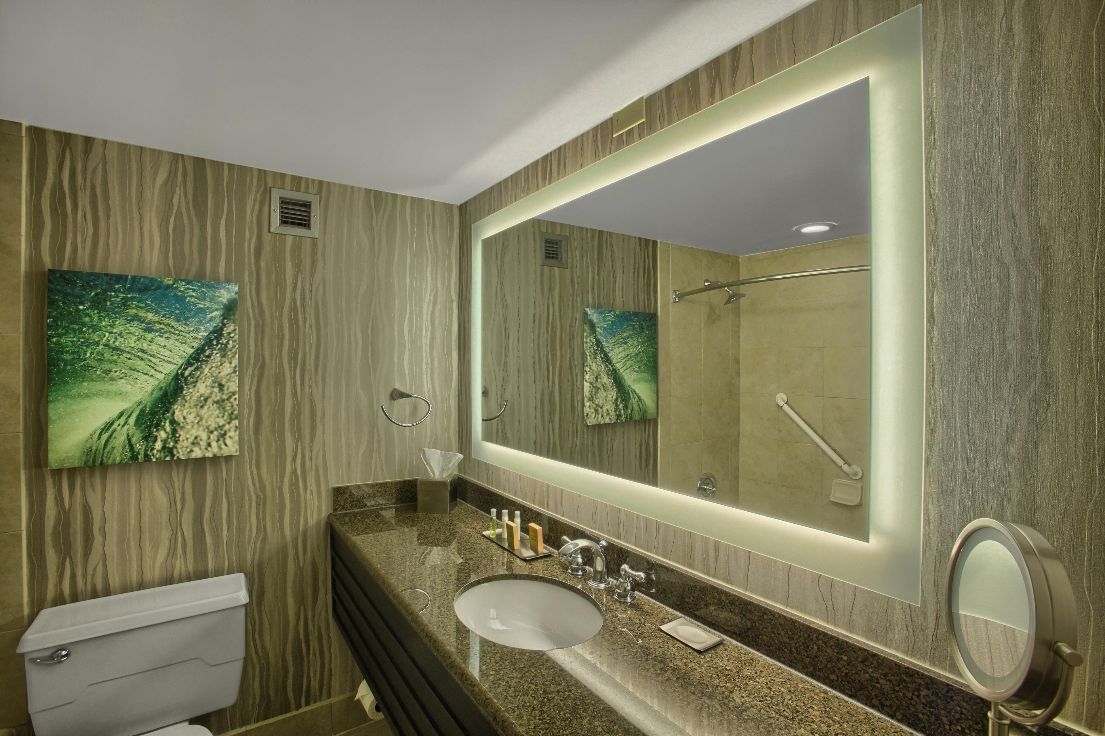 Une salle de bain avec des toilettes, un lavabo et un grand miroir.