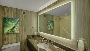 Un baño con inodoro, lavamanos y un espejo grande.
