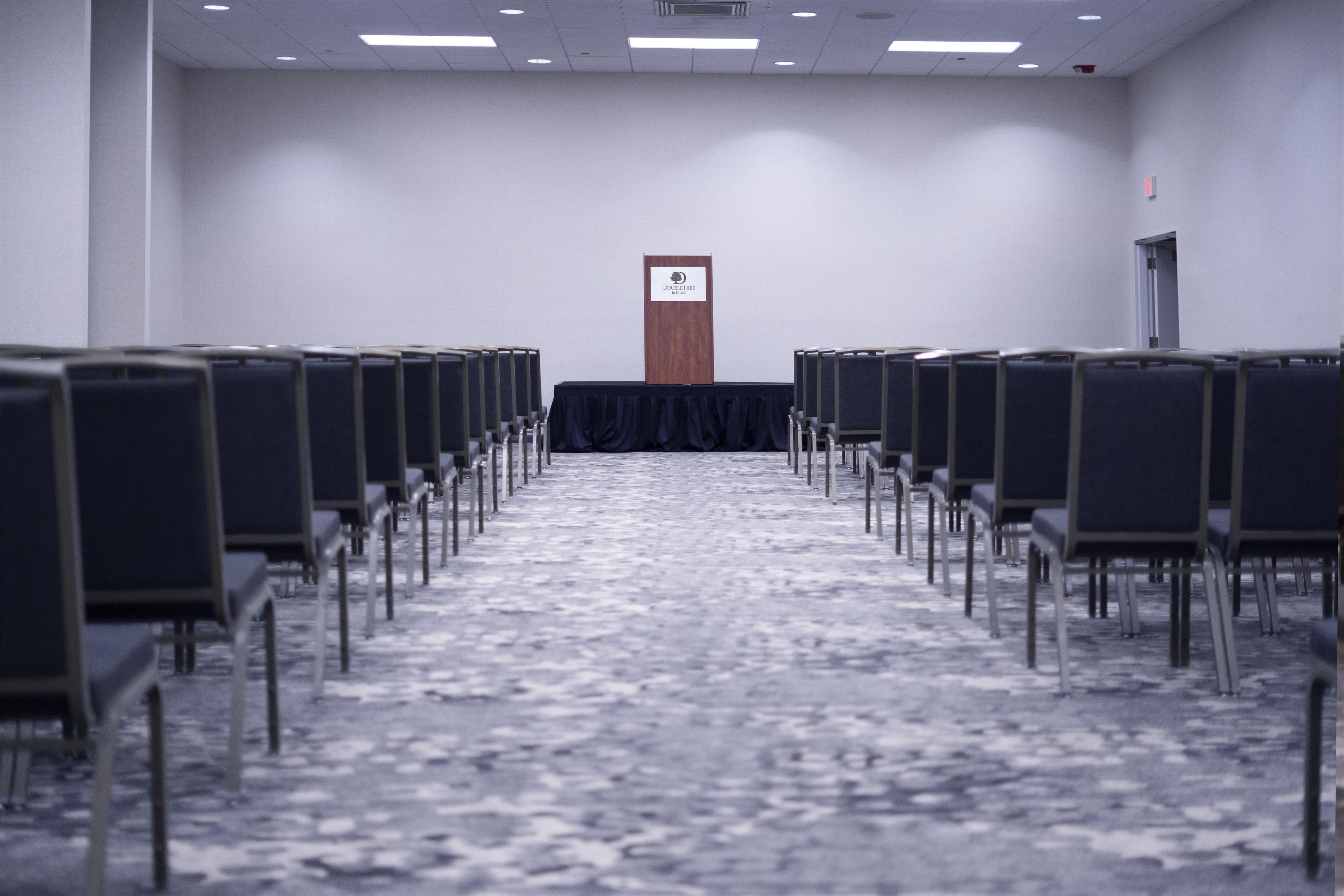 Une salle de conférence avec des rangées de chaises disposées face à un pupitre.