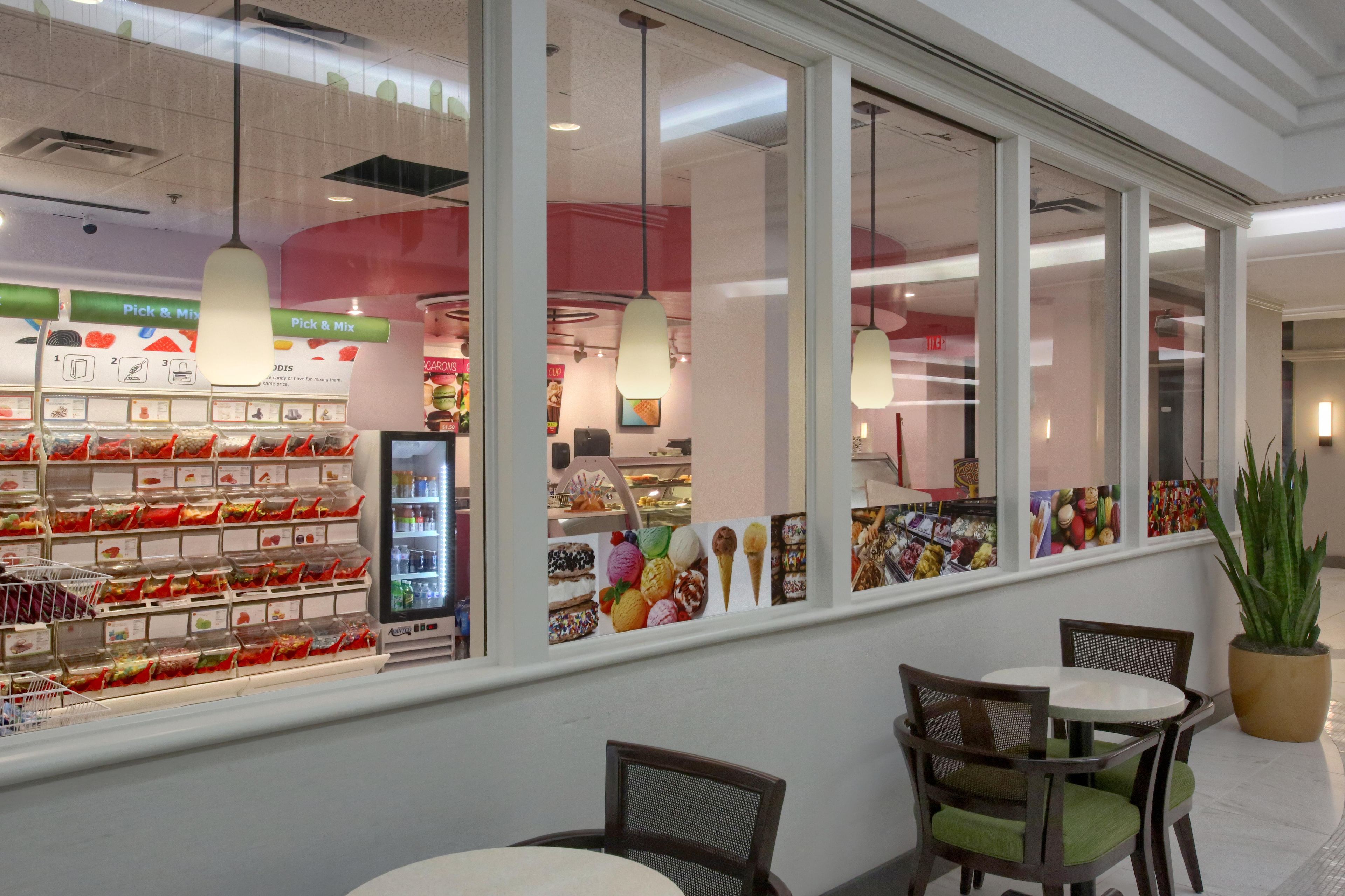 Interior de una cafetería con mostrador de surtido, zona de estar y un refrigerador.