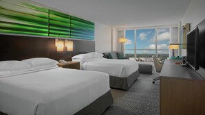 A hotel room with two beds, a desk, a TV, and a large window with a view. - DoubleTree by Hilton at the Entrance to Universal Orlando (Orlando)
