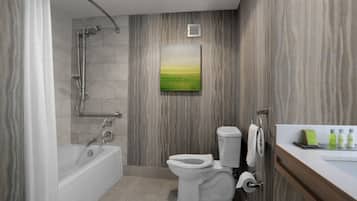 A modern bathroom with a bathtub, toilet, shower, and a painting on the wall.