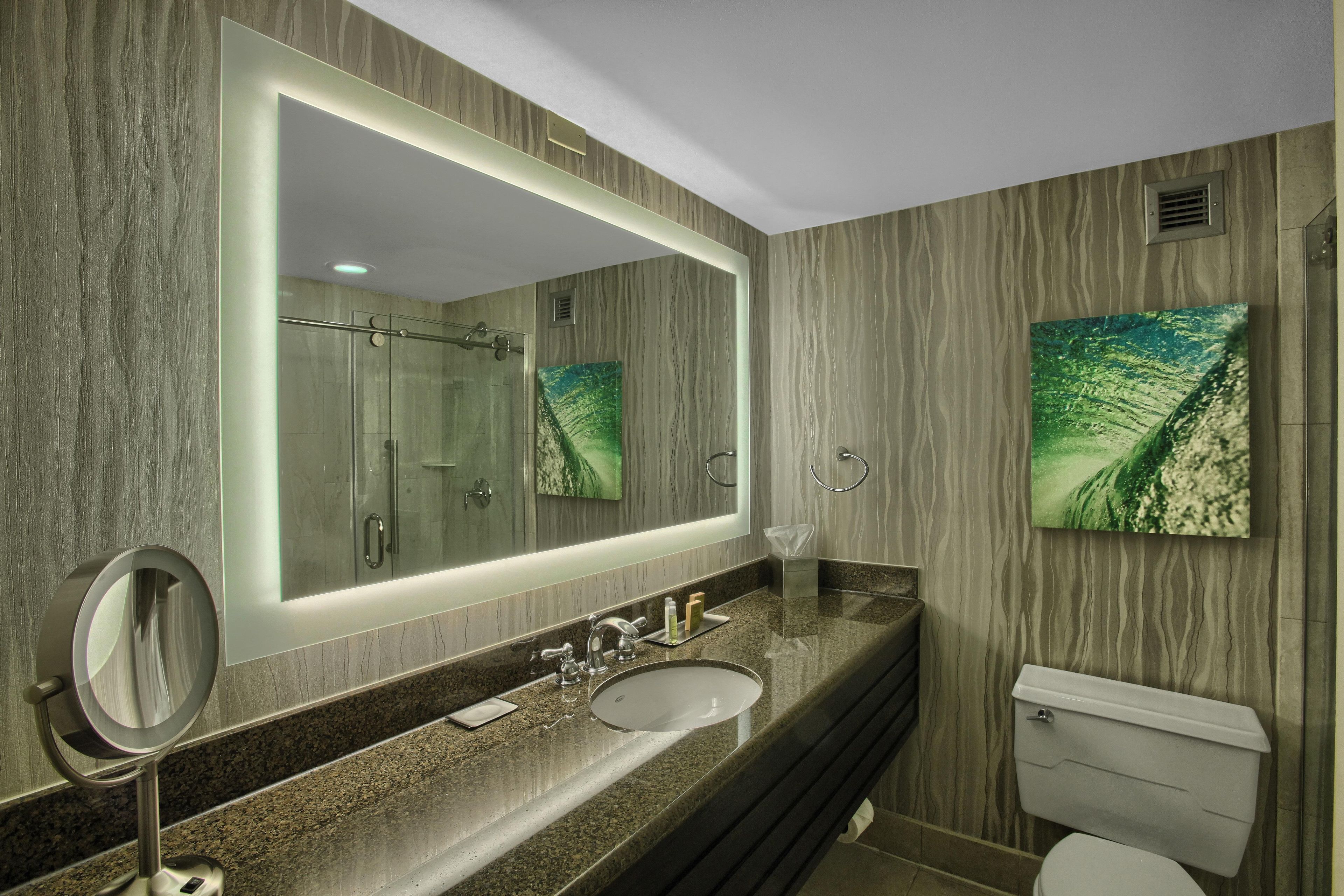 A modern bathroom with a large mirror, a sink, and a toilet.