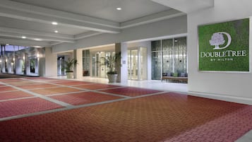 Eine großzügige Lobby mit rotem, gemustertem Boden, Glastüren und einem DoubleTree by Hilton Schild.