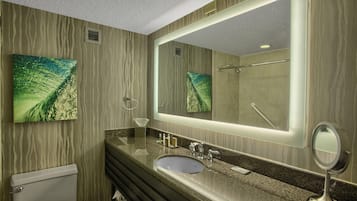 Een moderne badkamer met een granieten aanrechtblad, een grote spiegel en een toilet.