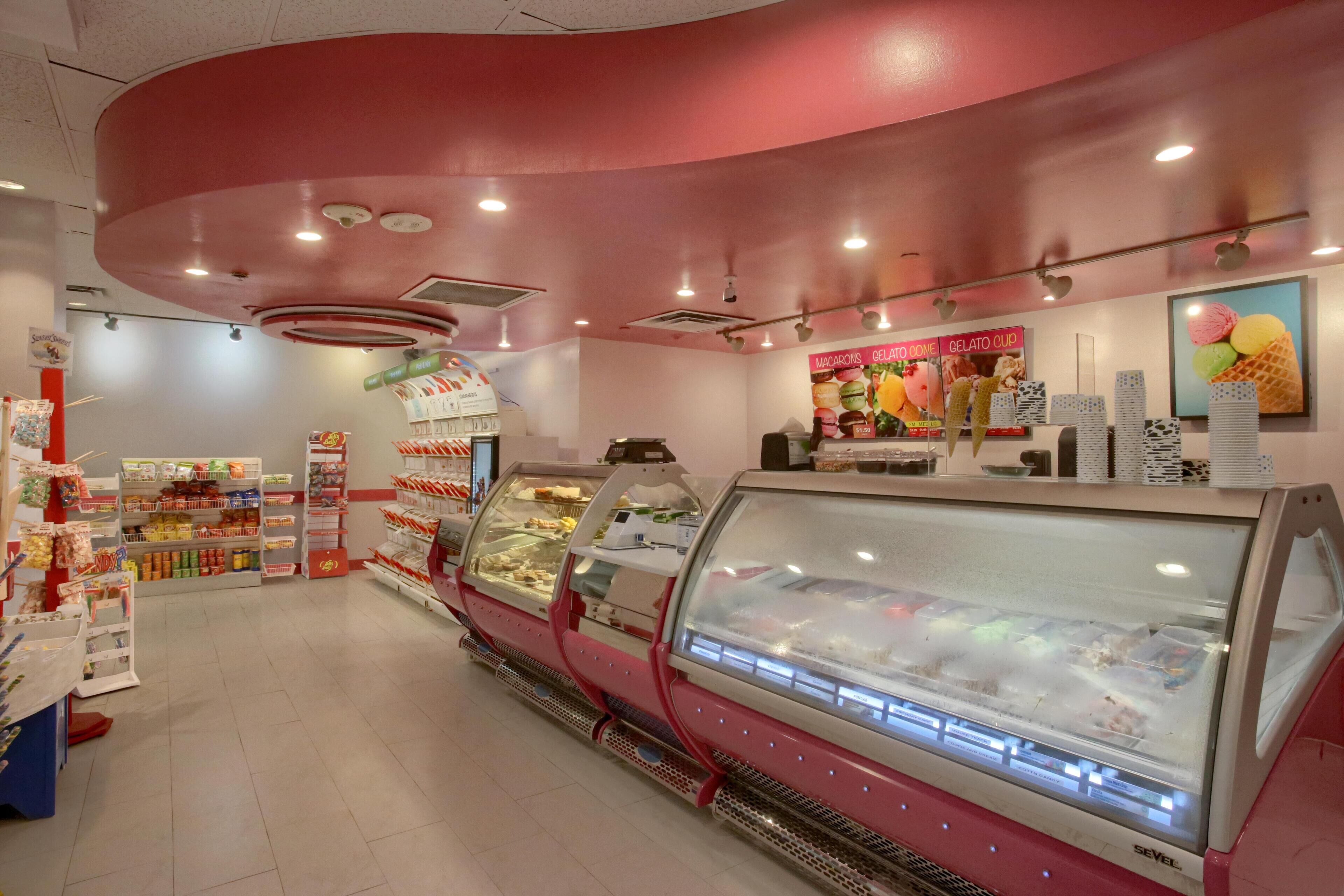 A gelato shop with a pink interior, refrigerated display cases, and a variety of gelato flavors.