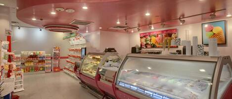Une boutique de gelato à l’intérieur rose, dotée de vitrines réfrigérées et proposant une grande variété de saveurs de gelato.