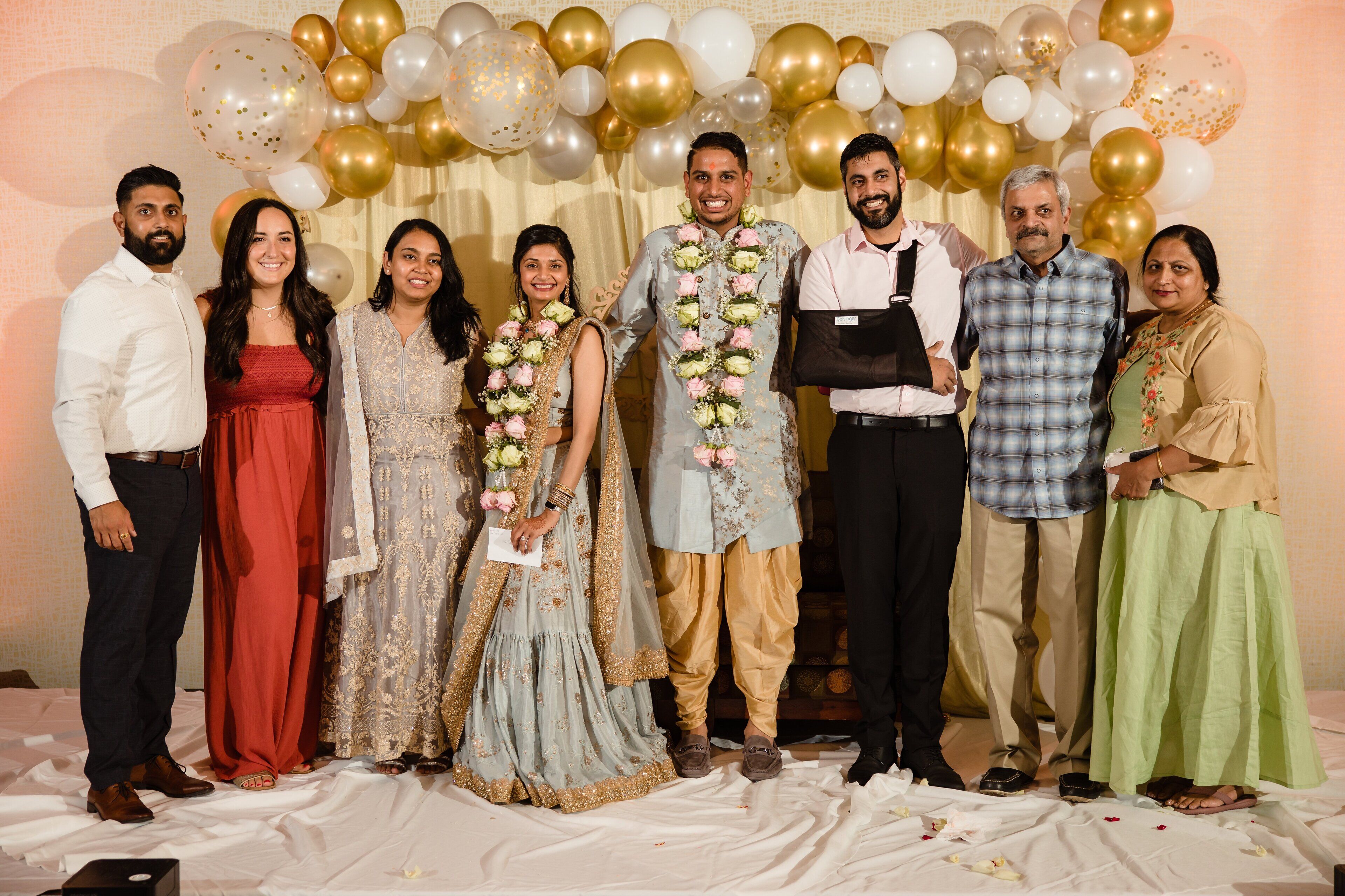 A group of people standing in front of a backdrop with balloons.